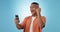 Man, phone and fist with cheers in studio for trading profit, success or revenue by blue background. Investor, trader or