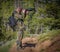 Man photographer in camouflage outfit with a backpack and tripod standing on a mountain forest trail and shooting