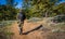 A man photographer hiking in camouflage outfit discovering nature in the forest with DSLR photo camera, lenses, tripod in the back