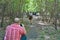 A man photographs a girl walking through the forest