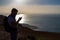 The man photographs an island in the ocean, standing on the edge of a cliff