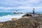 The man photographs waves crashing against a breakwater with a lighthouse near the marina. Villeneuve-Loubet. France