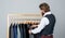 Man picking suit from personal wardrobe, tailored clothes concept