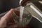 A man picks up drinking water in a glass from under the kitchen faucet