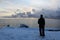 The man on the pier looks at the lake in the cold autumn