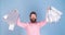 Man in pink shirt with happy face and long beard holding gift bags, birthday party, celebration concept. Hipster with