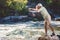 Man in pith helmet standing on rocky riverbank