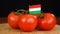 Man placing decorative toothpick with flag of Hungary into bunch of tomatoes.