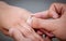 Man placing a diamond engagement ring on finger of his fiance