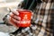 A man in a plaid shirt holding red enameled cup with coffeee or tea or hot drink