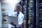 The man with the plan. Cropped shot of a IT technician working on his laptop while standing inside of a server room.