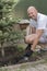 A man is planting a Christmas tree. Man Planting Small Christmas Tree In Silty Soil Ground With Bare Hands And Science Lab Beaker.