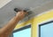 Man plastering window area with putty knife, closeup. Interior repair