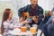 Man is playing acoustic guitar. Group of friends have party indoors together