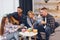 Man is playing acoustic guitar. Group of friends have party indoors together