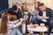 Man is playing acoustic guitar. Group of friends have party indoors together