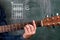 Man playing guitar chords displayed on a blackboard, Chord B