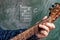 Man playing guitar chords displayed on a blackboard, Chord C