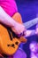 Man Playing an Orange Animal skinned guitar on stage with purple lighting background