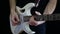 A man is playing a rhythm on a white electric guitar on a black background. Professional guitar playing.