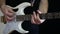 A man is playing a rhythm on a white electric guitar on a black background. Rock star.