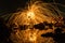 A man playing steel wool on the beach at night