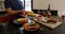 Man playing with tomato behind black table with fruit, vegetables, and bread