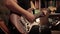 Man plays a brown-white electric guitar indoors while sitting on a sofa.