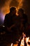 Man plays guitar and woman about the fire on the background of the starry sky