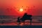 Man plays the piano on beach by the sea at sunset with birds flying in the sky