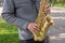 Man plays on saxophone in the park. Street musician with sax performs music for charity. Public solo performance by wind