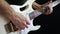 A man plays solo on a white electric guitar on a black background. Close-up.