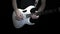 A man plays solo on a white electric guitar on a black background. Professional guitar playing.
