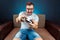 A man plays a video game console while sitting on a sofa. Day off, entertainment, leisure