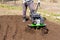 a man plowing the land with a motor-block, preparing the land for planting potatoes