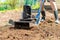 A man plows the ground in the garden with an electric cultivator