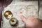 Man point with finger into red cross on Ancient Treasure map with compass on wooden desk