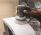 A man polishes the optics of a car\\\'s headlights with a polishing machine at a service station.
