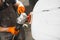 Man polishes white car in auto repair shop, close-up. Orbital polishing machine. Polished finishing.