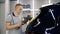 A man is polishing a car with a polishing machine. Car polishing. Car detailing - Hands with orbital polisher in auto