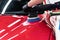 Man polishing car varnish with hand electric polisher.