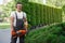 Man posing at garden with electric trimmer in hands