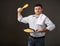 Man posing with a pancake in a pan, white shirt and pants, gray background