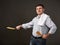 Man posing with a pancake in a pan, white shirt and pants, gray background