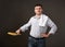 Man posing with a pancake in a pan, white shirt and pants, gray background