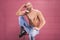 Man posing pink background shirtless muscular sitting stool