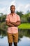 Man posing in pink button shirt with arms crossed. African American male model with deadpan expression and blurry background