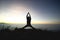 Man posing yoga on top of misty mountain cliff