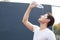 Man pouring fresh mineral water drinking water from clean bottle over his face outdoor under summer heat. Health care, Well being