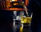 Man pouring glasses of whiskey with ice cubes in front of the fireplace